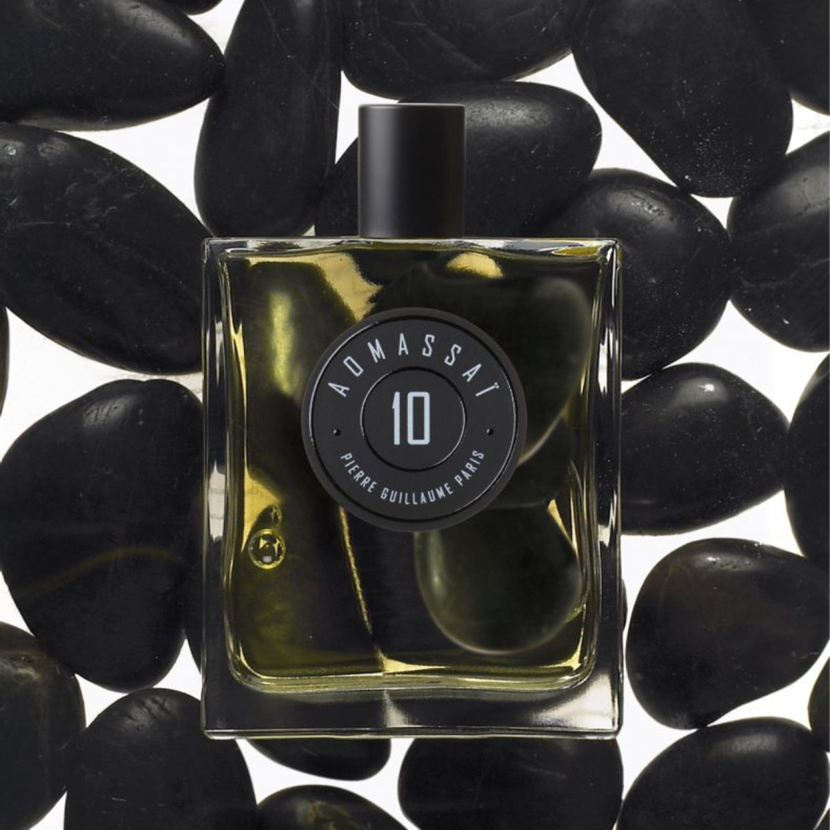 Perfume bottle labeled 'Admassal 10' on black stones