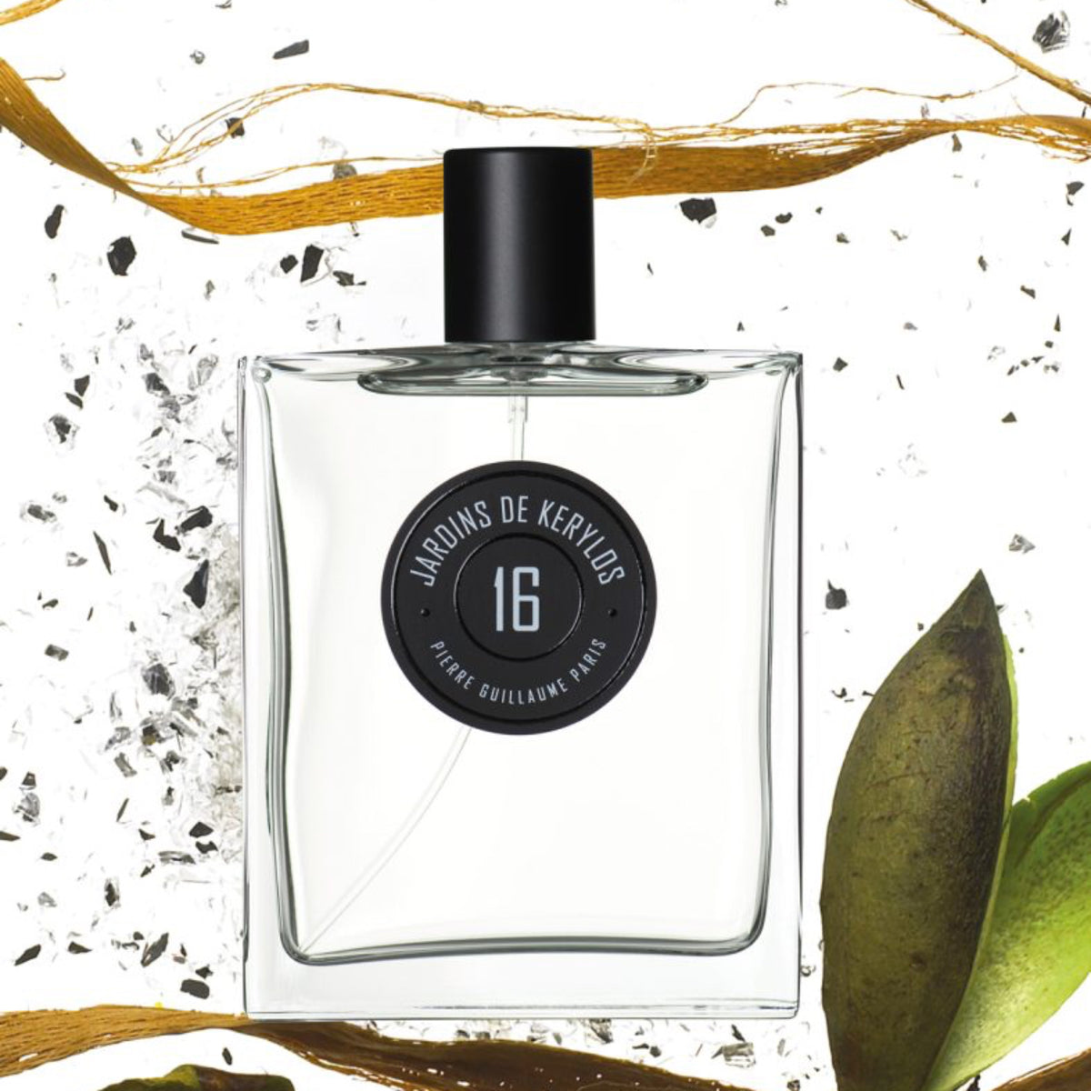 Perfume bottle with a black cap and label on a decorative background with leaves and gold ribbons.